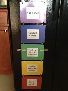 a black refrigerator with magnets on it in a kitchen