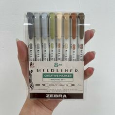 a hand holding a pack of zebra colored markers