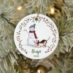 a christmas ornament with a dog and snowman on it hanging from a tree