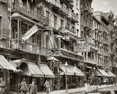 an old black and white photo of people walking down the street in front of buildings