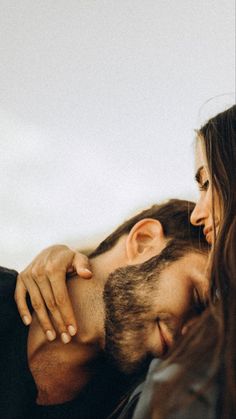 a man and woman embracing each other while they are looking into the distance with their eyes closed