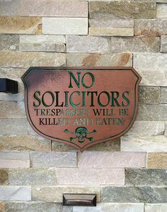 a sign that is on the side of a brick wall saying no solicitors trespassers will be killed and eaten