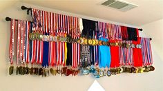 a bunch of medals are hanging on the wall next to each other with ribbons around them