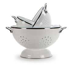 three white colanders stacked on top of each other in a bowl with handles