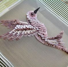 a pink and white bird made out of sequins on top of a pillow