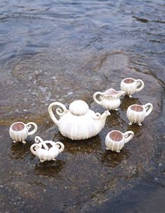 teapots and cups are sitting on the rocks in the water