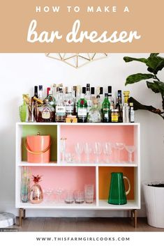 a white shelf filled with lots of bottles and glasses next to a potted plant