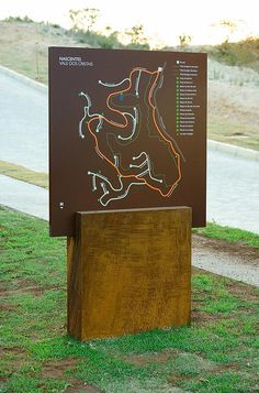 a sign in the middle of a grassy area with a road map on it's side