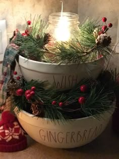 a candle is lit in a bowl with pine branches and berries on the rim, surrounded by other christmas decorations