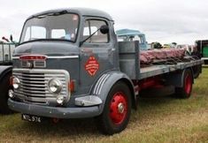 an old truck is parked in the grass near other trucks and traileres on display