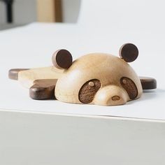 a small wooden bear laying on top of a white surface