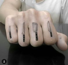 a man with tattoos on his fingers holding up two knives in front of the camera