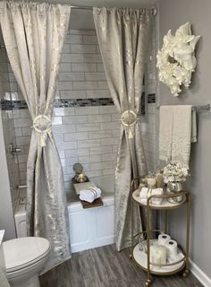 a white toilet sitting next to a bath tub in a bathroom on top of a hard wood floor