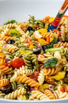 a colorful pasta salad with broccoli, tomatoes, olives and other vegetables