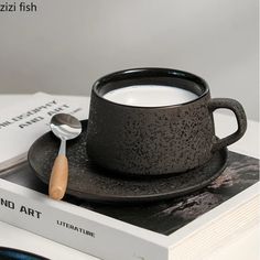 a cup of milk sitting on top of a book next to a spoon