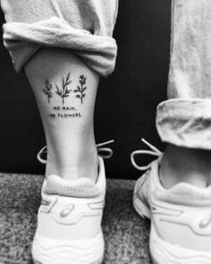 two people standing next to each other with tattoos on their legs, one has the words no rain, and the other has flowers