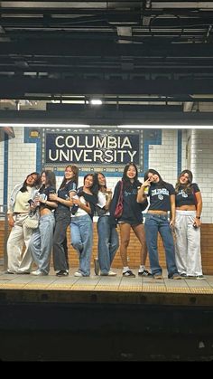 a group of young women standing on top of a train platform next to each other