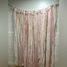 a pink and white curtain hanging from the side of a wall next to a wooden floor