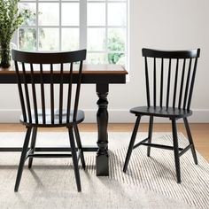 a dining room table with two chairs and a rug on the floor in front of it