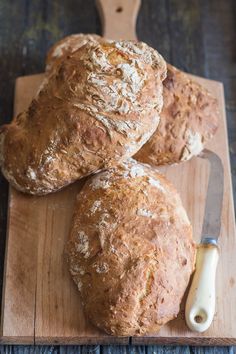 three loaves of bread on a cutting board with a knife