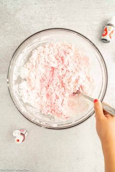 someone is mixing ingredients in a bowl with a spoon on the table next to them