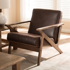 a brown chair sitting in front of a table with a lamp on top of it