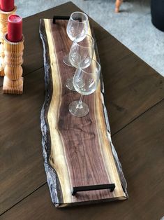 two wine glasses sitting on top of a wooden table next to candles and vases