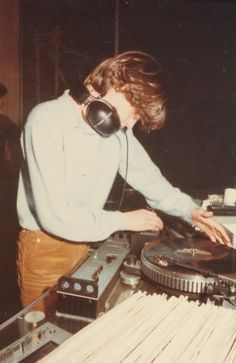 a man standing next to a record player on top of a turntable with headphones