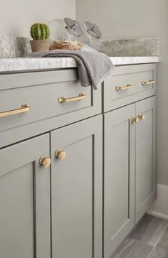 a kitchen with gray cabinets and gold pulls on the handles, along with a white counter top