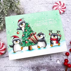 a christmas card with penguins and a tree on the front, surrounded by candy canes