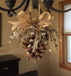 a chandelier hanging from the ceiling with pine cones and flowers on it's branches