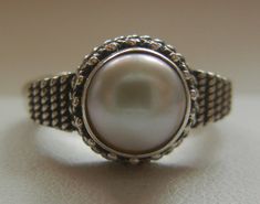 "Bali Suarti sterling silver and pearl ring. Small and beautiful, this ring has a soft iridescent white pearl, set in a raised bezel. The slightly domed pearl is encased in two rows of fine granulation pebbles and two rows of fine braiding. The sides have a striped-pebble vertical design. The back of the setting is solid and the band is thick. Beautifully made in the Balinese tradition and in excellent vintage condition. Please see detailed measurements below. > Size 5.5. *Thank you for doubl Silver Braided Ring, Feather Ring Silver, Iridescent White, Lapis Ring, Feather Ring, Braided Ring, Vertical Design, Bezel Ring, White Band