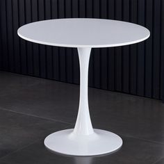 a white table sitting on top of a tiled floor next to a black and white wall