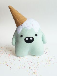 a green stuffed animal with an ice cream cone on top of it's head