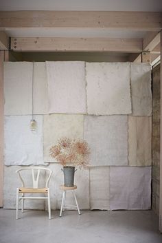 a white chair sitting next to a vase with flowers in it on top of a table