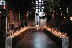 a long table is set up in the middle of a room with lights hanging from the ceiling