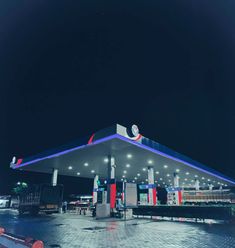 an empty gas station at night with lights on the roof and no people around it