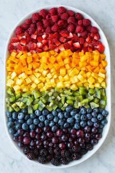 a bowl filled with berries, kiwis and other fruits on top of a marble counter