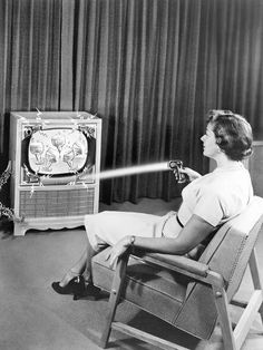 an old woman sitting in a chair watching cartoons on the television set with her dog