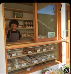 a woman standing in front of a display case filled with food