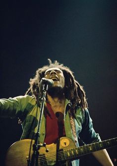 bob marley singing into a microphone and holding a guitar in his right hand with the words, i've got to go looking for happiness