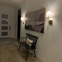 a black chair sitting on top of a hard wood floor next to a white wall