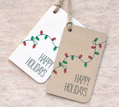 two tags that say happy holidays and have christmas lights hanging from the strings on them