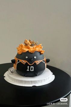 a black and white cake with an orange crown on it's head sitting on top of a table