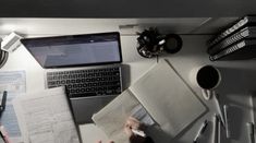 a person sitting at a desk with papers, laptop and other office supplies on it