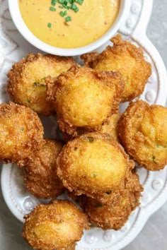 some fried food is on a plate next to a bowl of soup and dipping sauce