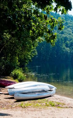 two canoes sitting on the shore of a lake