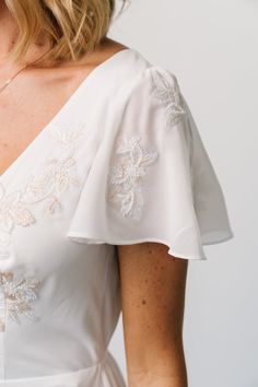 Experience modern elegance with a vintage twist in our Swan Bead Embroidered Midi Dress. Adorned with stunning floral embroidery and delicate beaded details, this piece features a deep V-neckline and flutter-style embroidered sleeves, ensuring timeless sophistication for any occasion. Elegant V-neck Dress With Intricate Embroidery, Fitted V-neck Dress With Embroidered Neckline, Elegant V-neck Dress With Embroidered Neckline, Fitted Cream Dress With Intricate Embroidery, Fitted V-neck Embroidered Dress For Wedding, Fitted Dress With Embroidered Sleeves For Wedding, Elegant Cream Dress With Flutter Sleeves, Fitted Cream Dress With Pearl Embroidery, Elegant Summer Embroidered Dress With Embroidered Sleeves