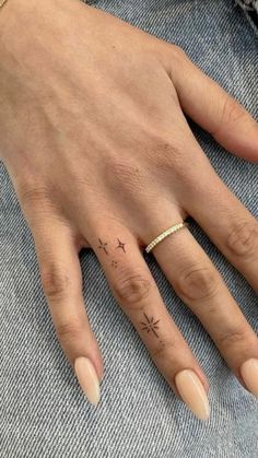 a woman's hand with a small star tattoo on her left thumb and ring