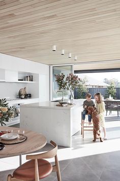 two people sitting at a table in a kitchen with an open floor plan and sliding glass doors